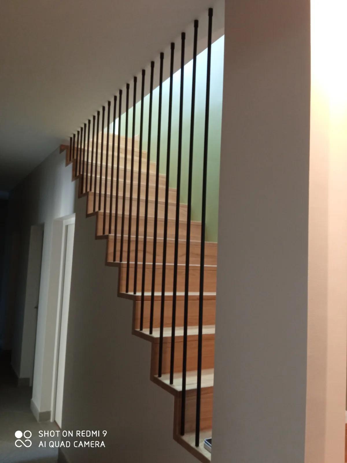 Escalier design en métal avec des marches en bois et un garde-corps minimaliste.